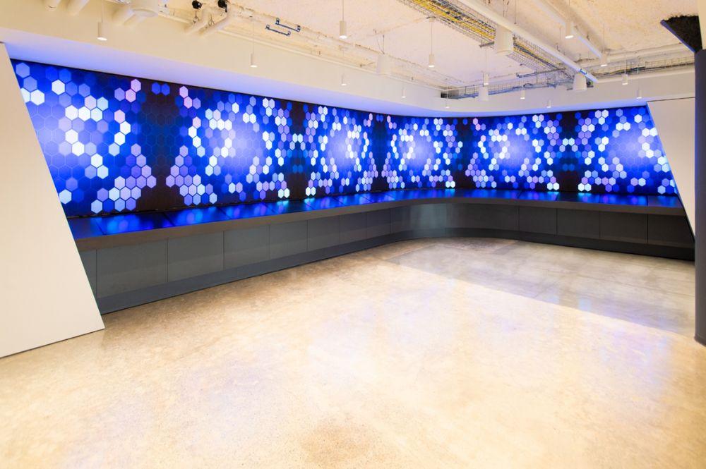 A large multi-colored digital canvas display wraps around the corner of a room.