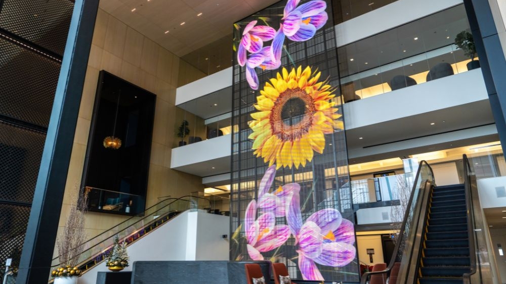 A large mural of flowers in the lobby, enhanced by transparent mesh displays for a vibrant visual effect.