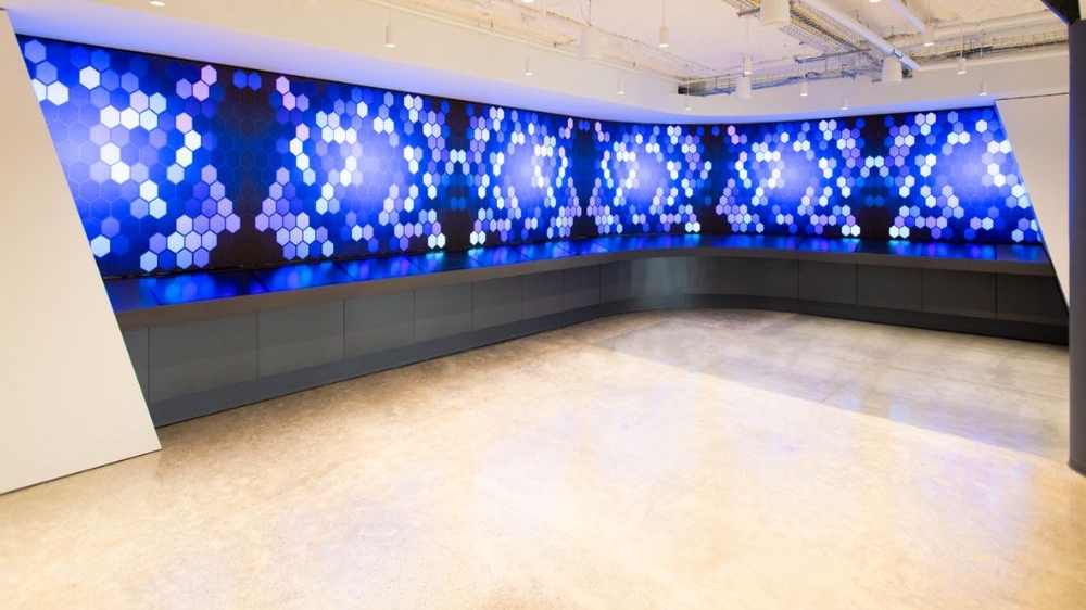 A large multi-colored digital canvas display wraps around the corner of a room.