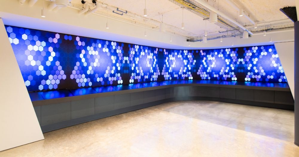 A large multi-colored digital canvas display wraps around the corner of a room.